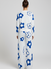 Person wearing a white outfit with blue floral patterns on a plain background