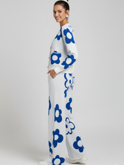 Woman wearing a white outfit with blue floral patterns on a plain background